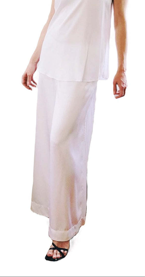 Woman wearing a white sleeveless top and pants on a white background