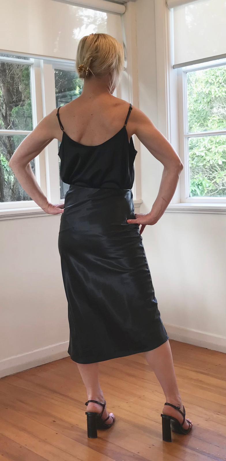 Person wearing a black skirt with top standing in a room with large windows.