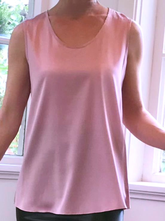 Person wearing a silk pink sleeveless top with a window in the background